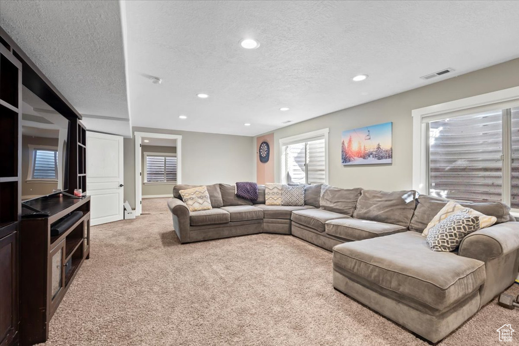 Living room featuring a textured ceiling, recessed lighting, visible vents, and light carpet