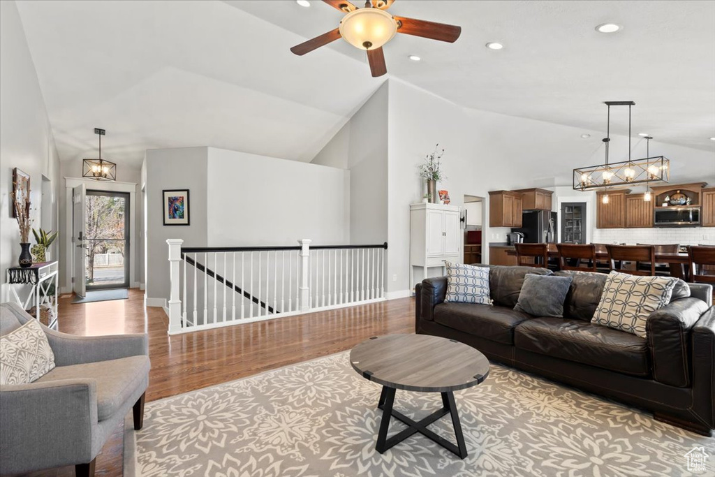 Living room featuring baseboards, a chandelier, recessed lighting, wood finished floors, and high vaulted ceiling