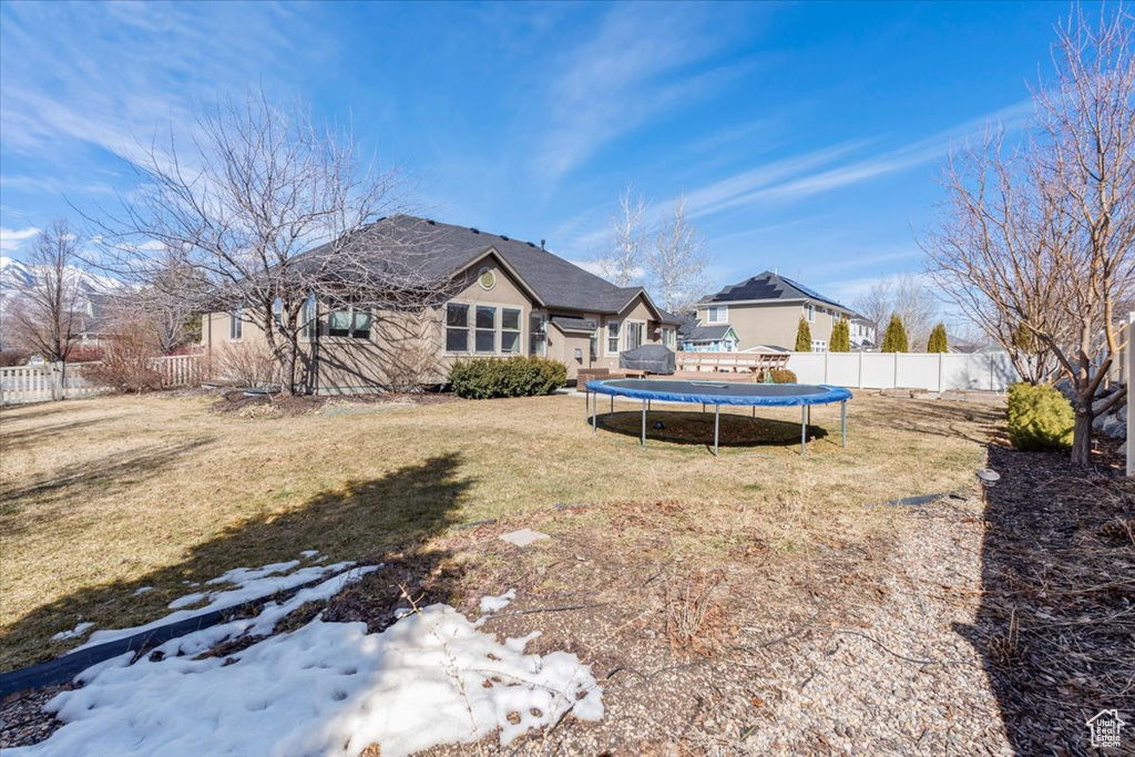 View of yard with a trampoline and fence