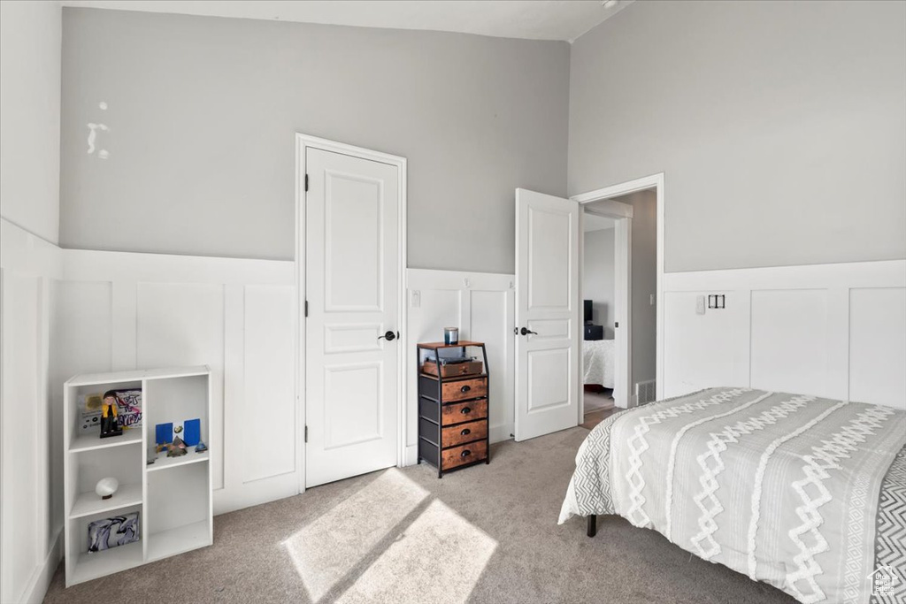 Bedroom with lofted ceiling, carpet, and a decorative wall