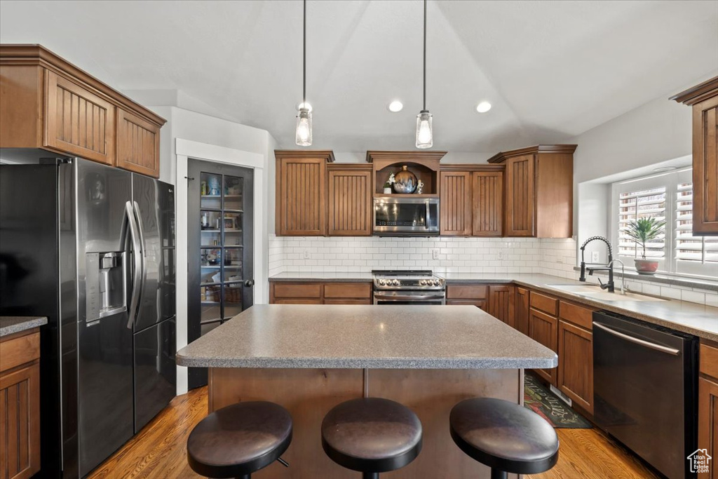 Kitchen featuring a sink, stainless steel appliances, backsplash, and vaulted ceiling