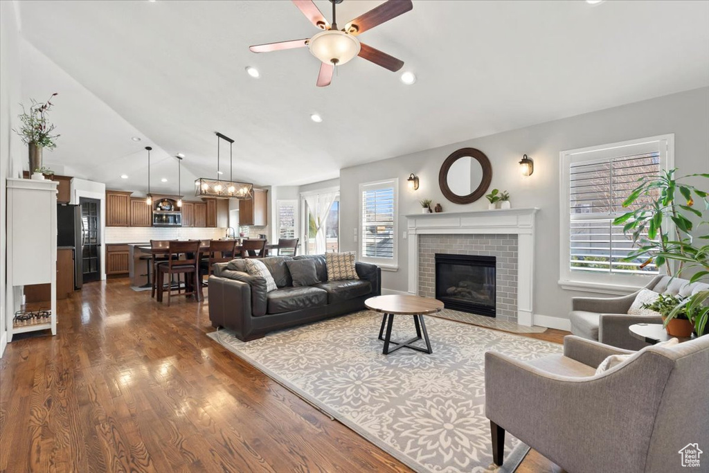 Living room with a brick fireplace, dark wood finished floors, vaulted ceiling, recessed lighting, and a ceiling fan