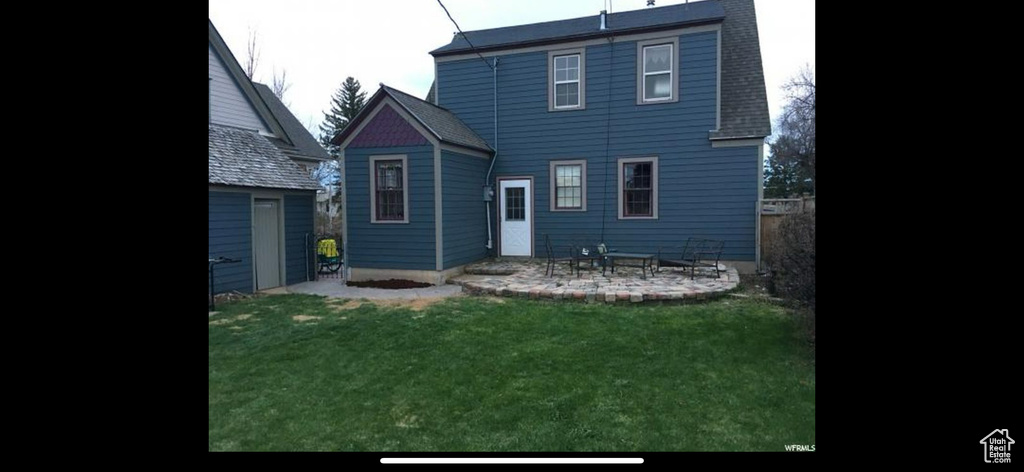 Rear view of house with a patio and a lawn