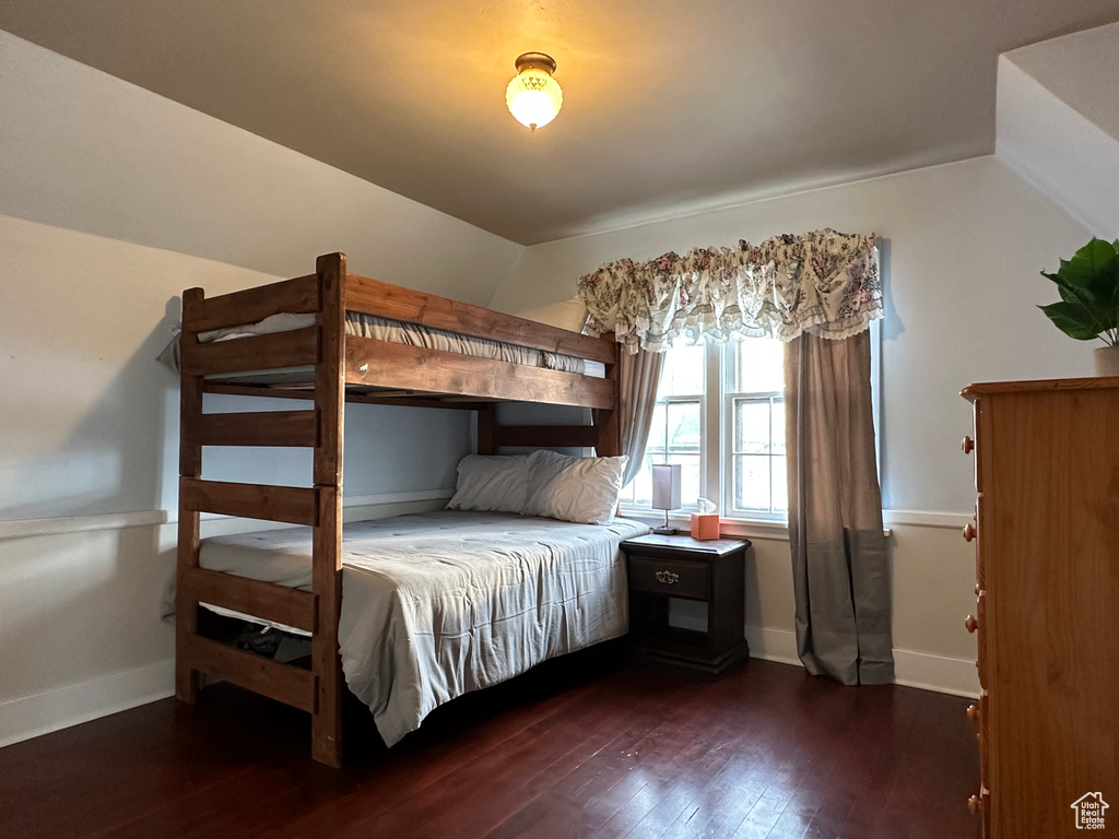 Unfurnished bedroom featuring vaulted ceiling, dark wood-style floors, and baseboards
