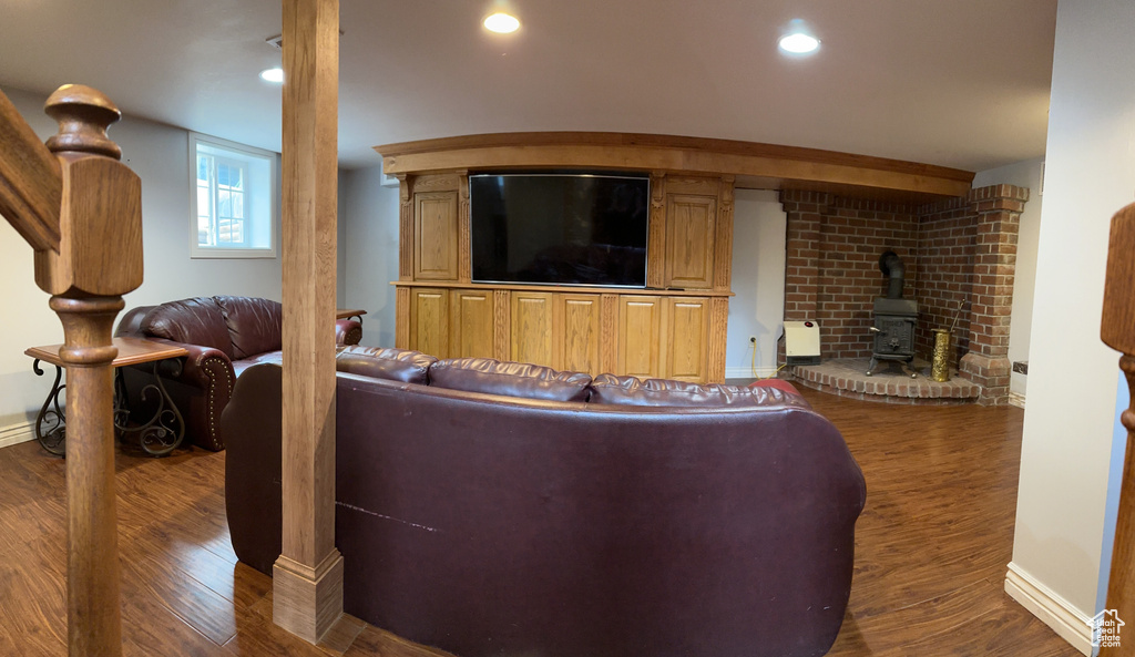 Living room with a wood stove, recessed lighting, wood finished floors, and baseboards