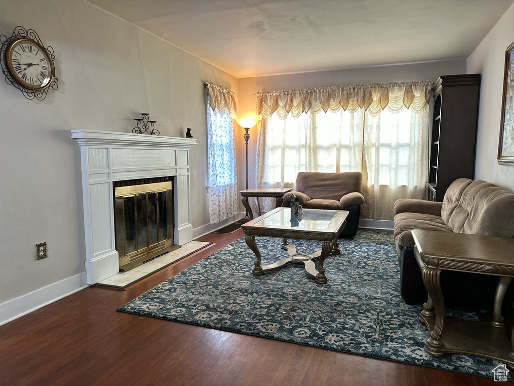 Living area with a tiled fireplace, wood finished floors, and baseboards