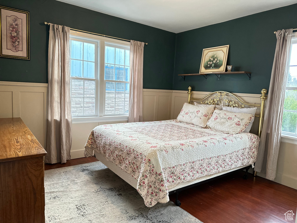 Bedroom with multiple windows, wood finished floors, and wainscoting