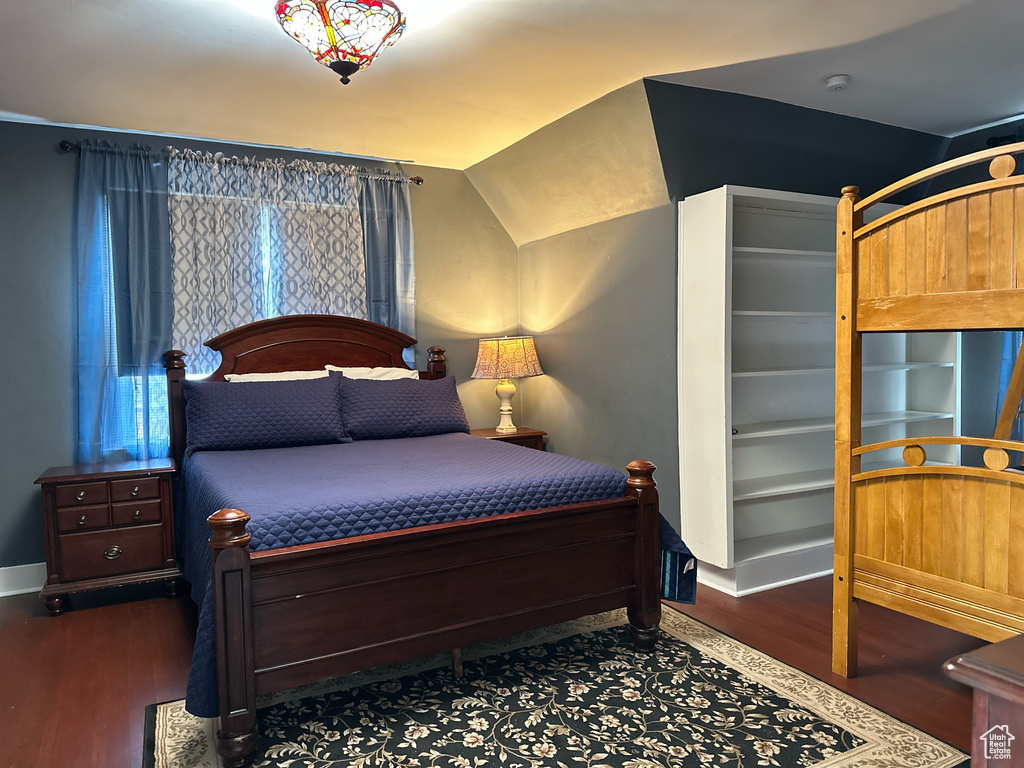 Bedroom with baseboards, lofted ceiling, and wood finished floors