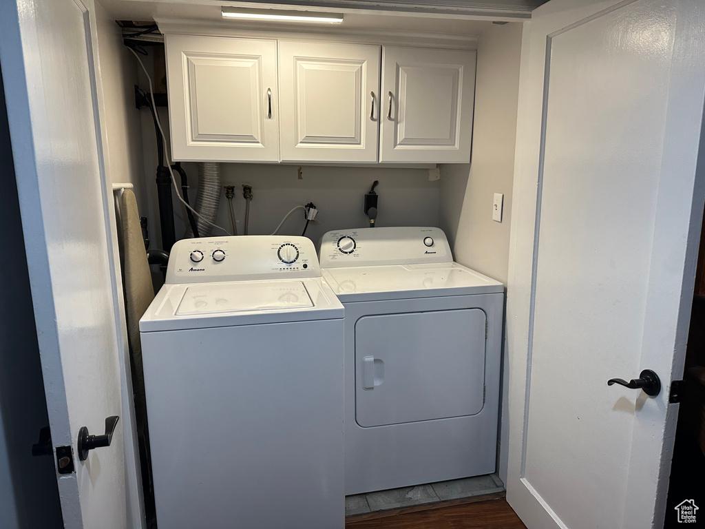 Washroom with dark wood-style floors, cabinet space, and washer and dryer