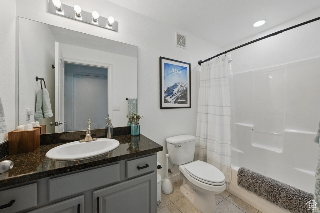 Bathroom featuring vanity, visible vents, tile patterned flooring, shower / tub combo, and toilet