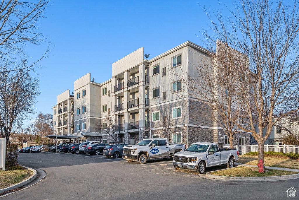 View of building exterior with uncovered parking and fence