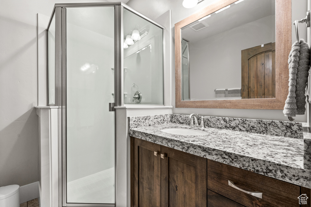 Bathroom with vanity, toilet, visible vents, and a stall shower