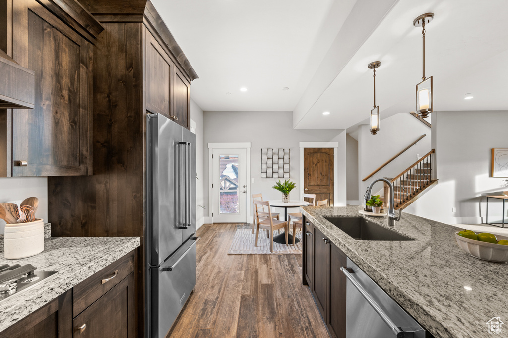 Kitchen featuring dark wood-style floors, dark brown cabinets, stainless steel appliances, and a sink