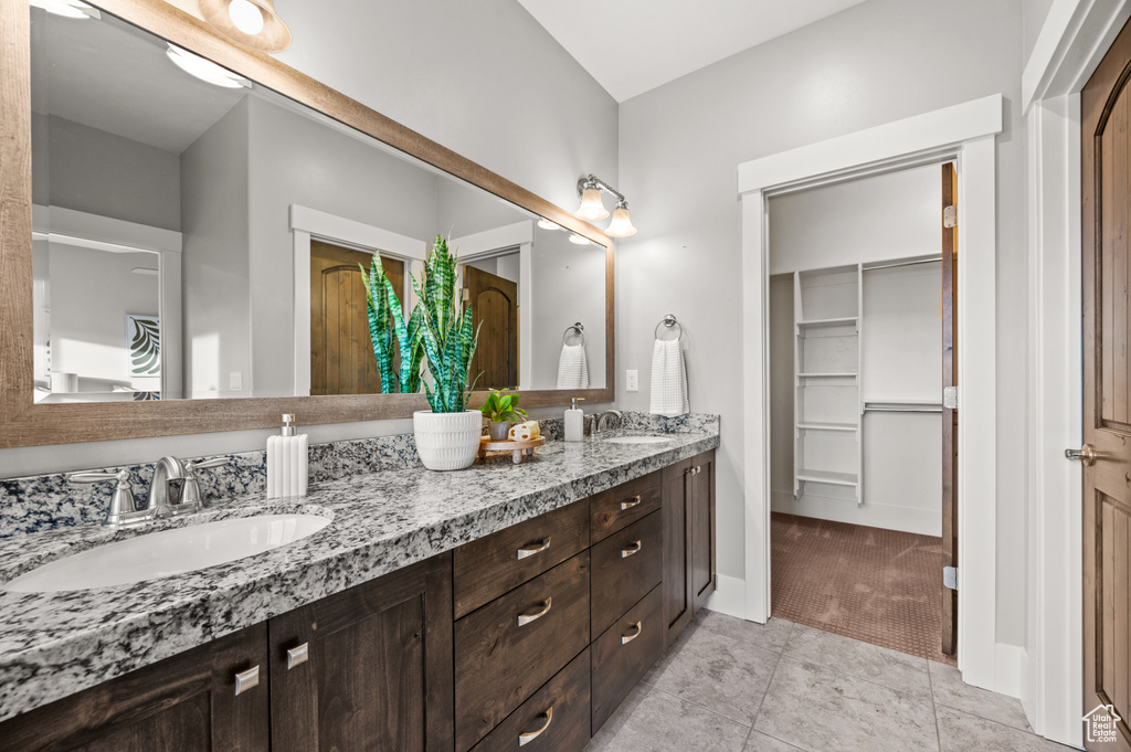 Bathroom with a walk in closet, double vanity, baseboards, and a sink