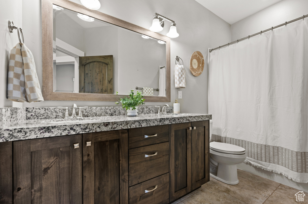 Full bath with a sink, toilet, double vanity, and tile patterned floors