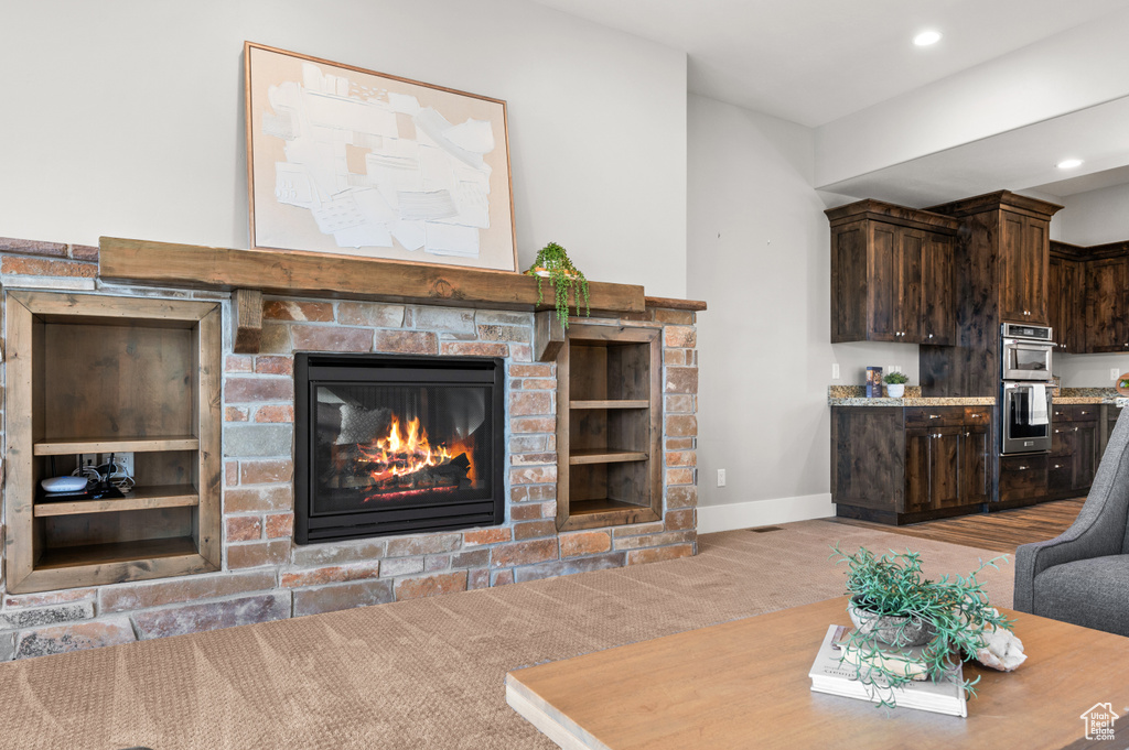 Living area featuring recessed lighting, a glass covered fireplace, carpet flooring, and baseboards
