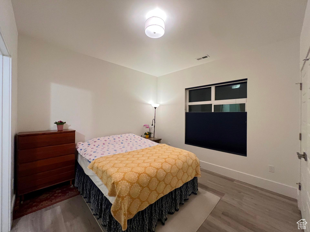 Bedroom with visible vents, baseboards, and wood finished floors