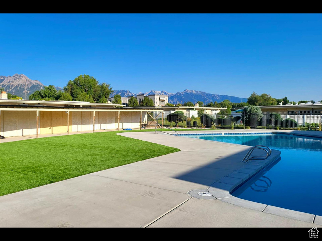 View of swimming pool with a fenced in pool, a mountain view, a yard, and fence