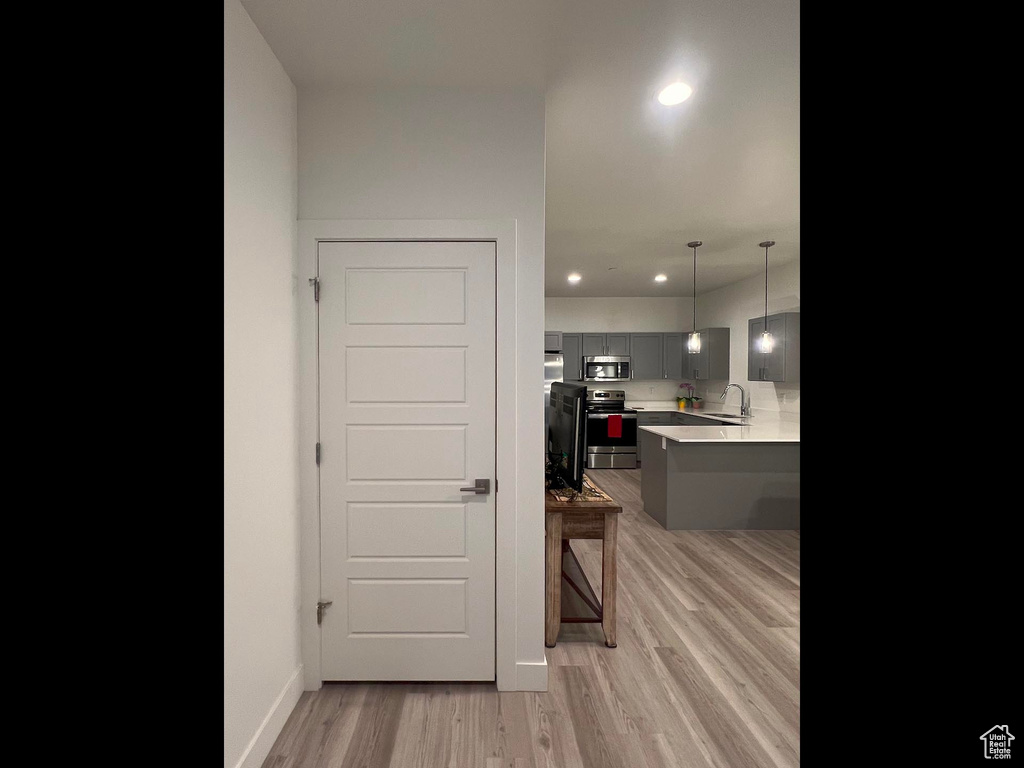 Kitchen with light countertops, a kitchen bar, light wood-style flooring, gray cabinets, and appliances with stainless steel finishes