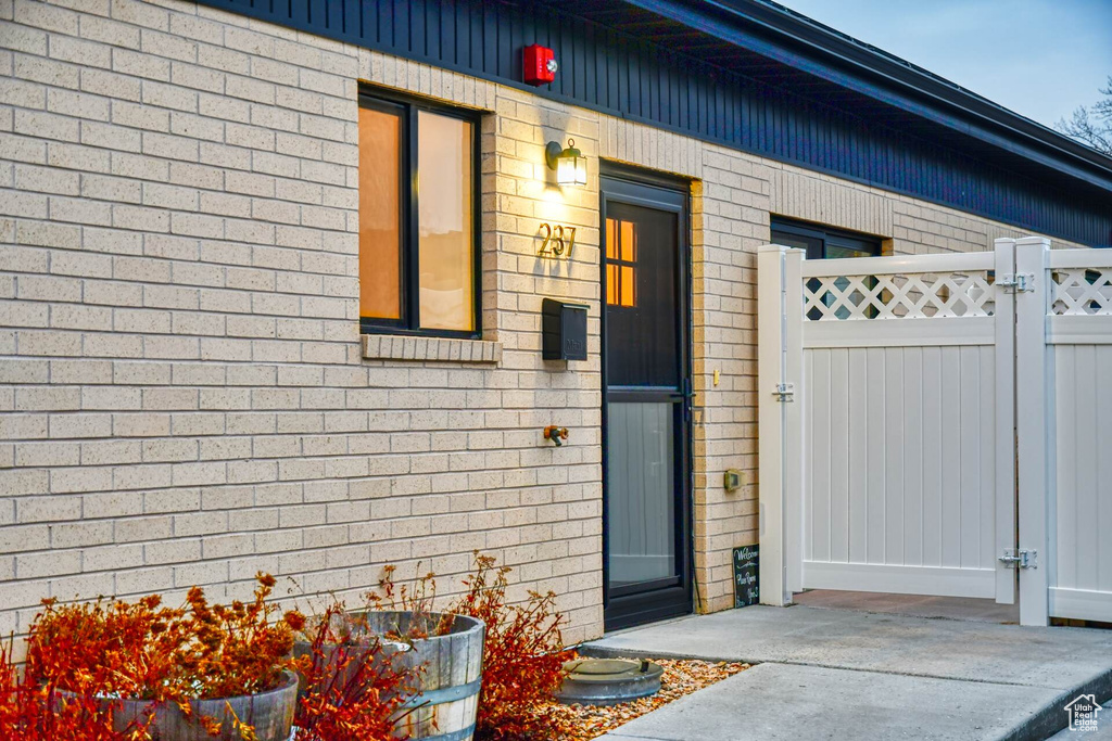 Property entrance featuring brick siding, fence, and a gate