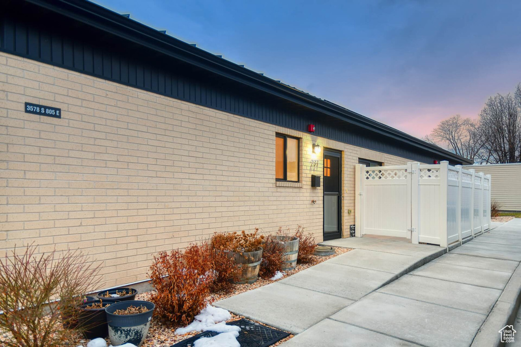 Property entrance featuring fence, brick siding, and a gate