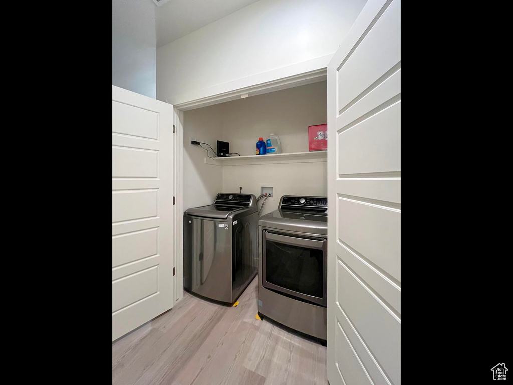 Washroom featuring light wood-type flooring, laundry area, and washer and clothes dryer