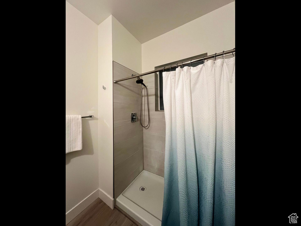 Bathroom with baseboards, tiled shower, and wood finished floors