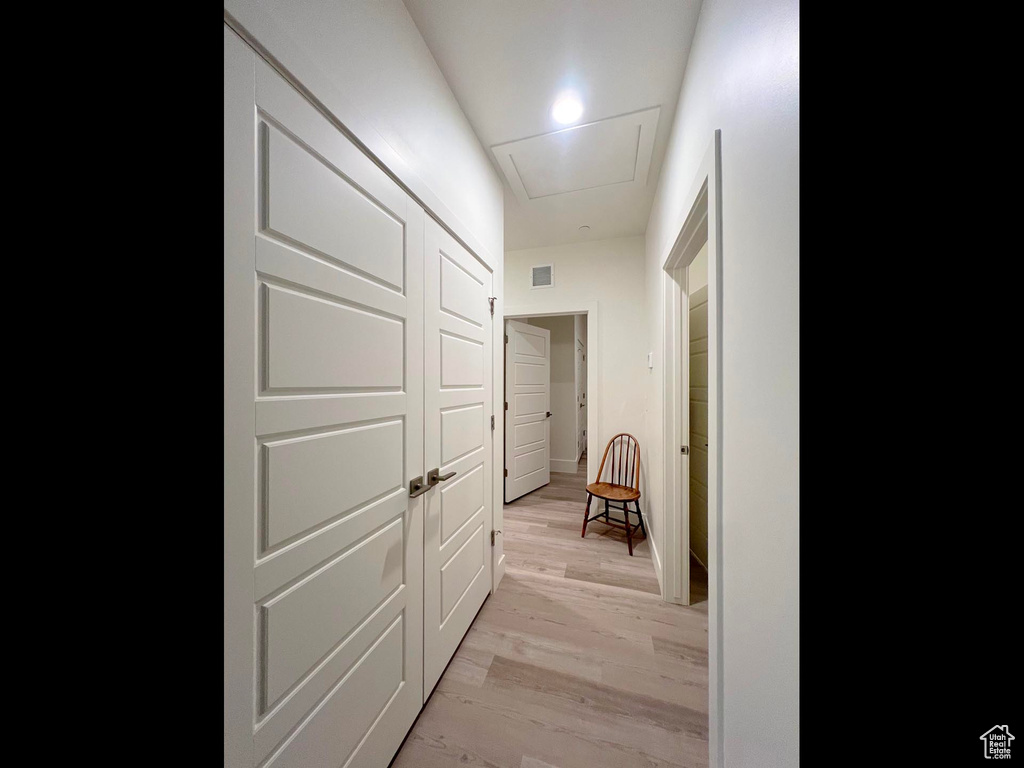 Hallway featuring attic access, visible vents, and light wood-type flooring