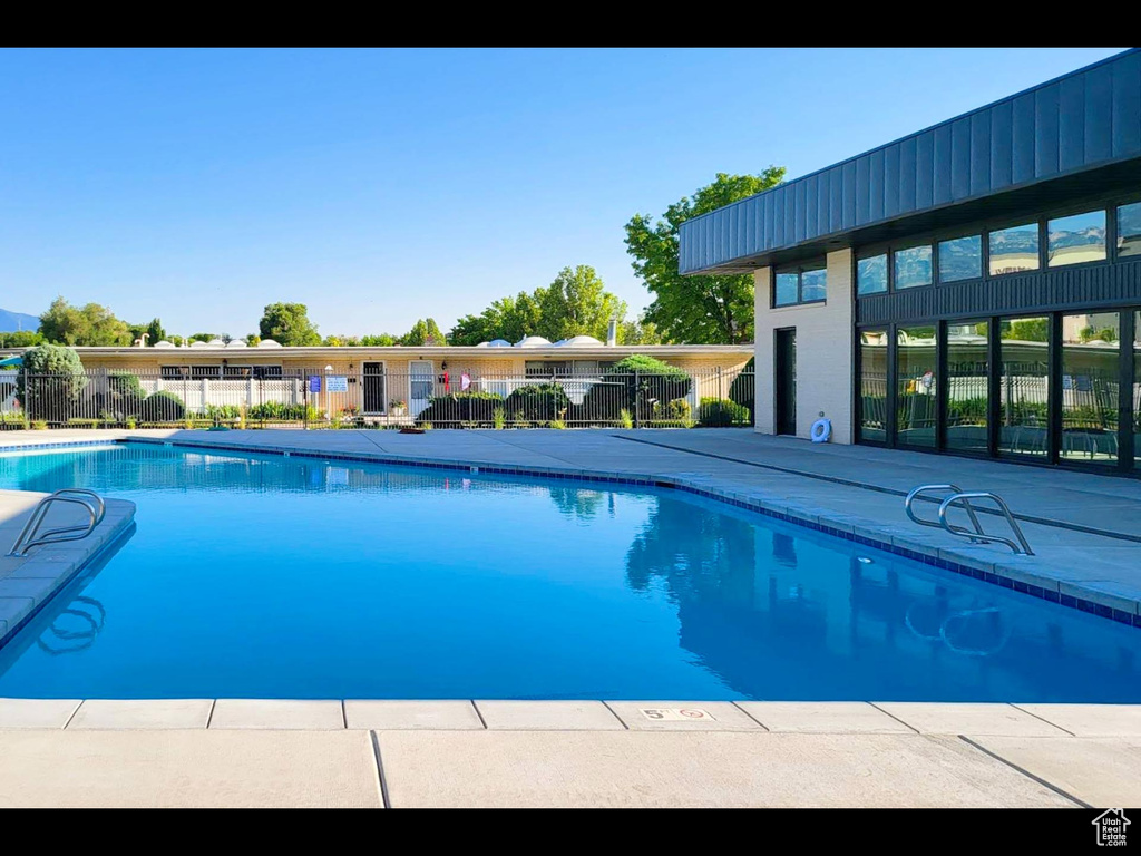 Community pool featuring a patio and fence