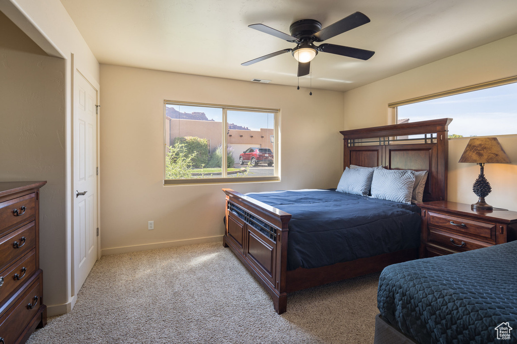 Bedroom featuring visible vents, multiple windows, light colored carpet, and baseboards
