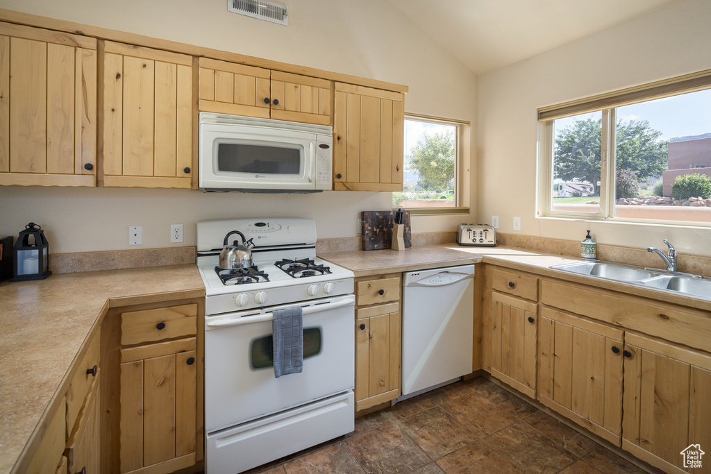 Kitchen with visible vents, light brown cabinets, a sink, white appliances, and lofted ceiling