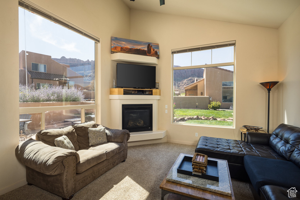 Living area featuring a glass covered fireplace, lofted ceiling, carpet, and a wealth of natural light