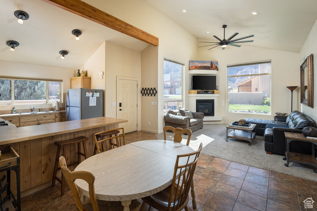 Dining space featuring ceiling fan, vaulted ceiling, recessed lighting, a glass covered fireplace, and dark colored carpet