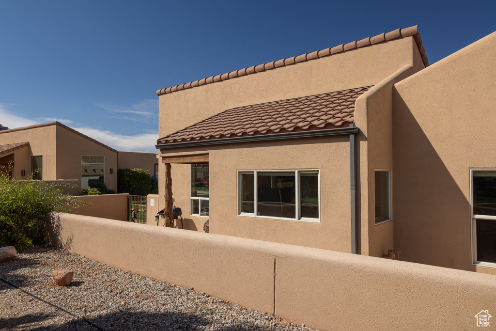 Back of house featuring stucco siding, a tiled roof, and fence
