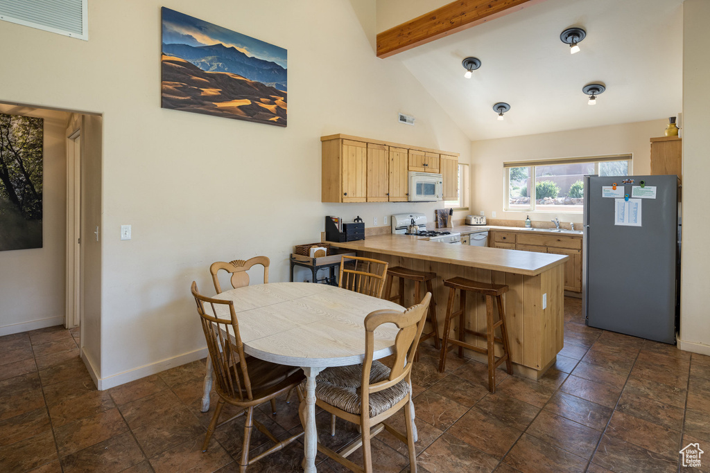 Dining space featuring visible vents, beam ceiling, high vaulted ceiling, and baseboards