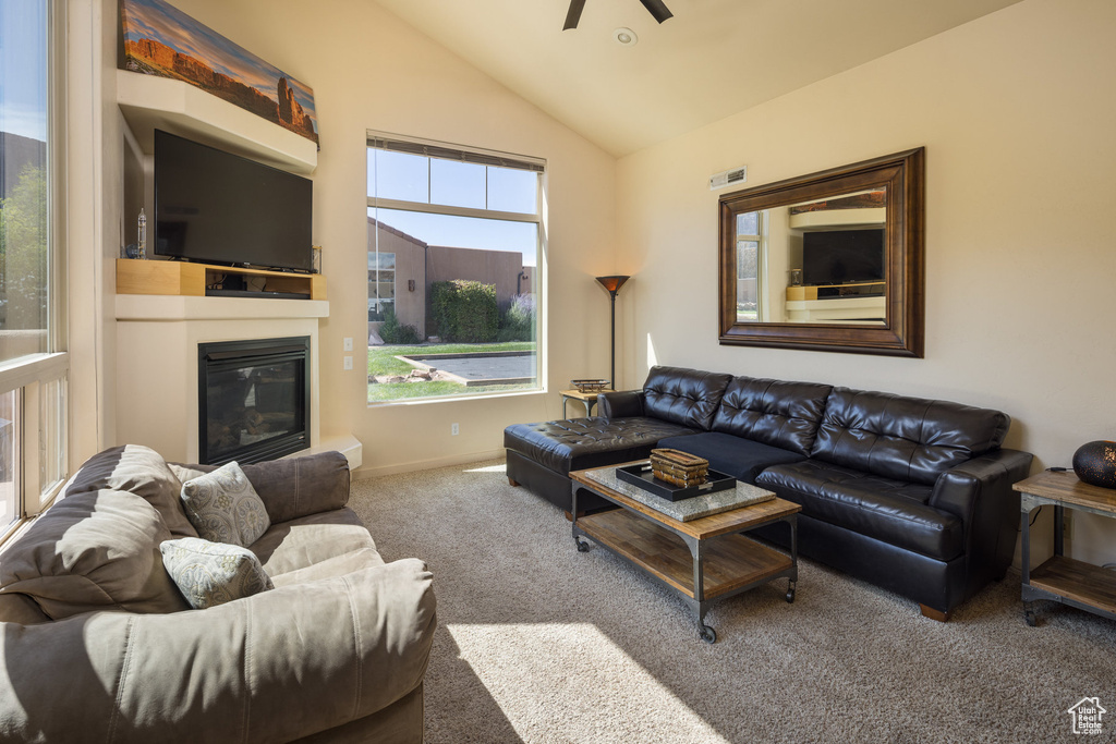 Living area with carpet, baseboards, lofted ceiling, ceiling fan, and a glass covered fireplace
