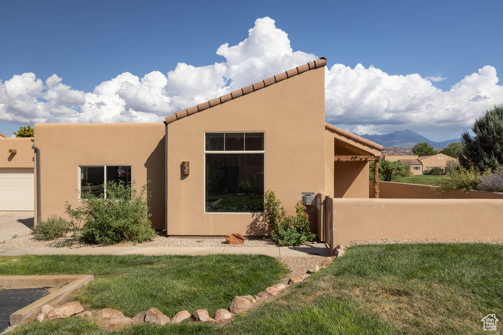 View of front of house featuring a front yard, a garage, a mountain view, and stucco siding