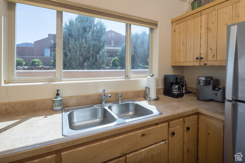 Kitchen featuring light brown cabinets, light countertops, freestanding refrigerator, and a sink