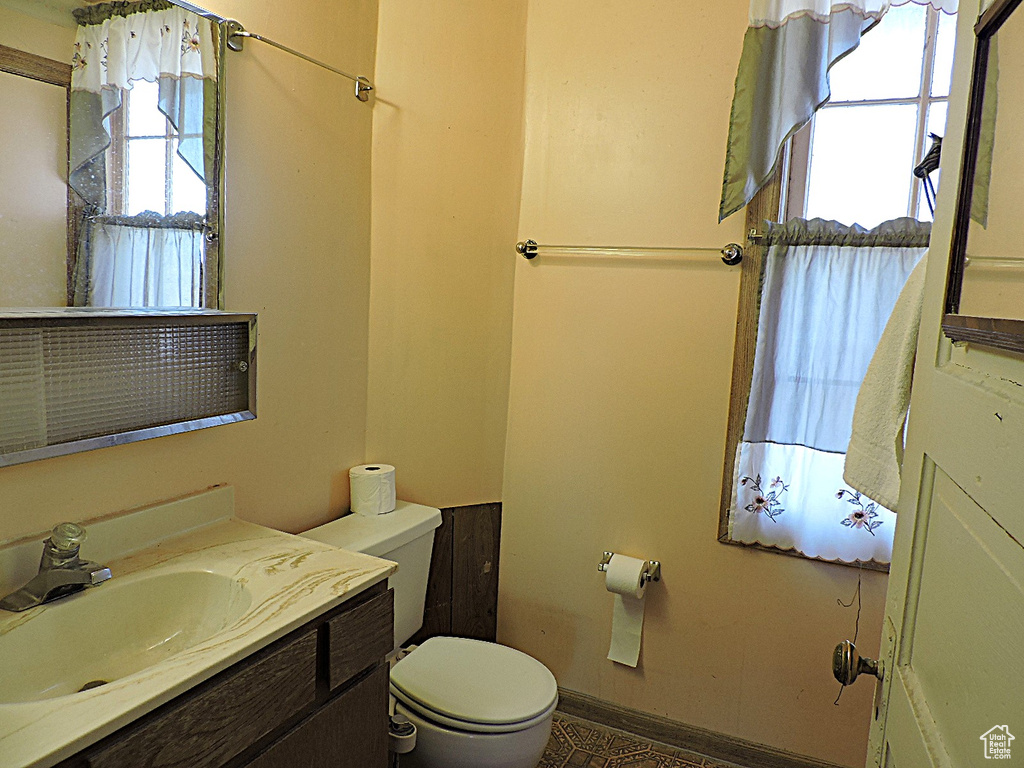 Bathroom featuring a wealth of natural light, baseboards, toilet, and vanity