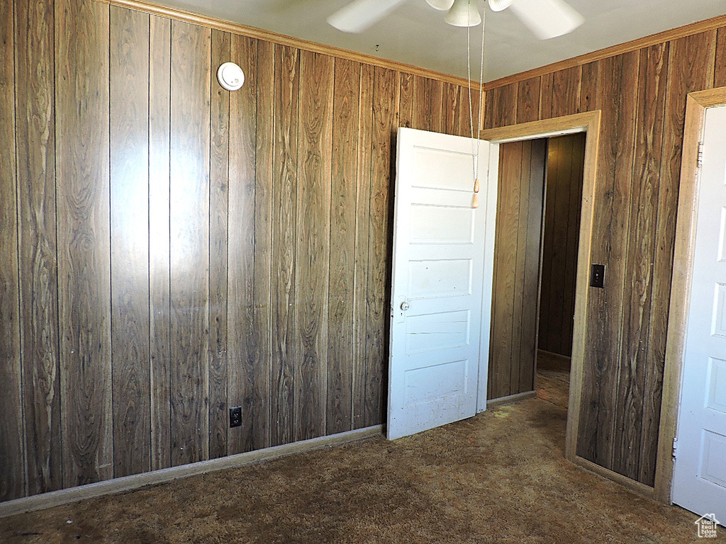 Unfurnished bedroom featuring wood walls and carpet floors