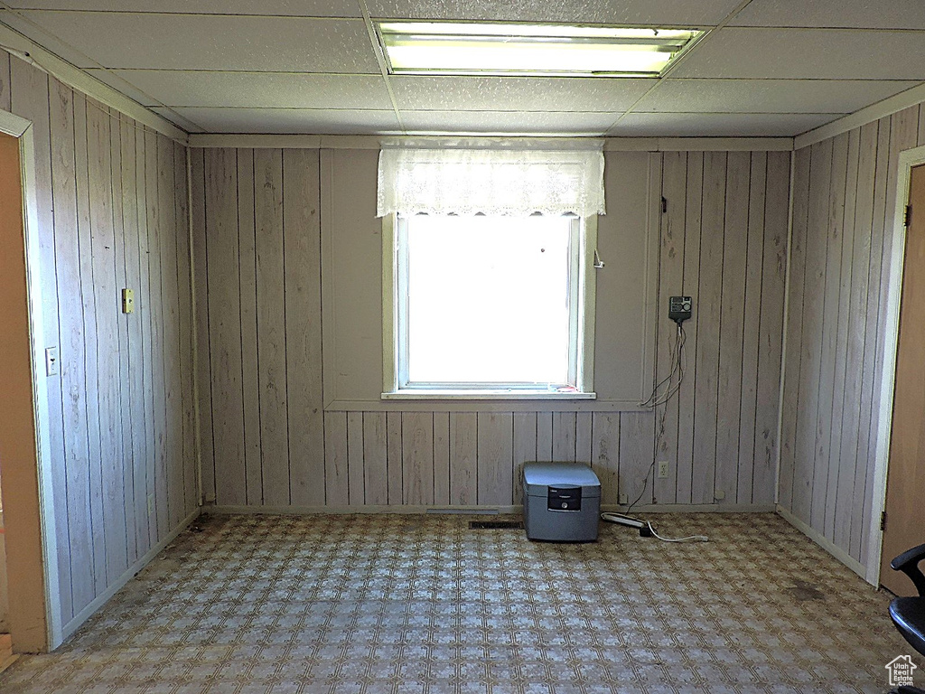 Spare room with tile patterned floors, wooden walls, and a drop ceiling