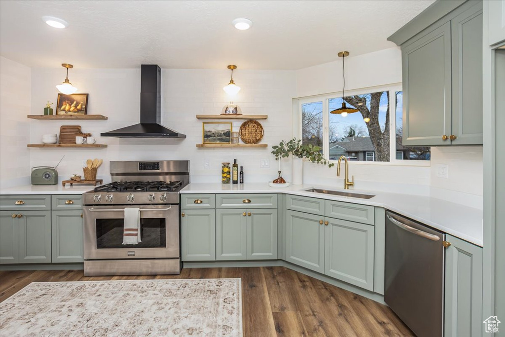 Kitchen with a sink, green cabinets, wall chimney range hood, stainless steel appliances, and open shelves