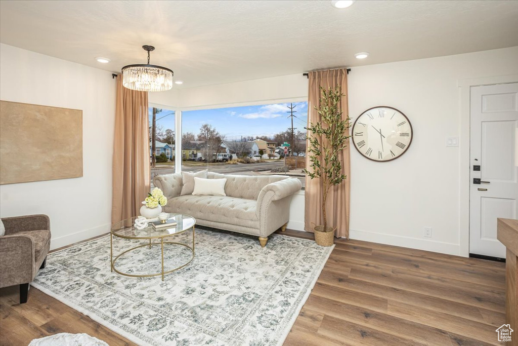 Living room with recessed lighting, baseboards, a notable chandelier, and wood finished floors