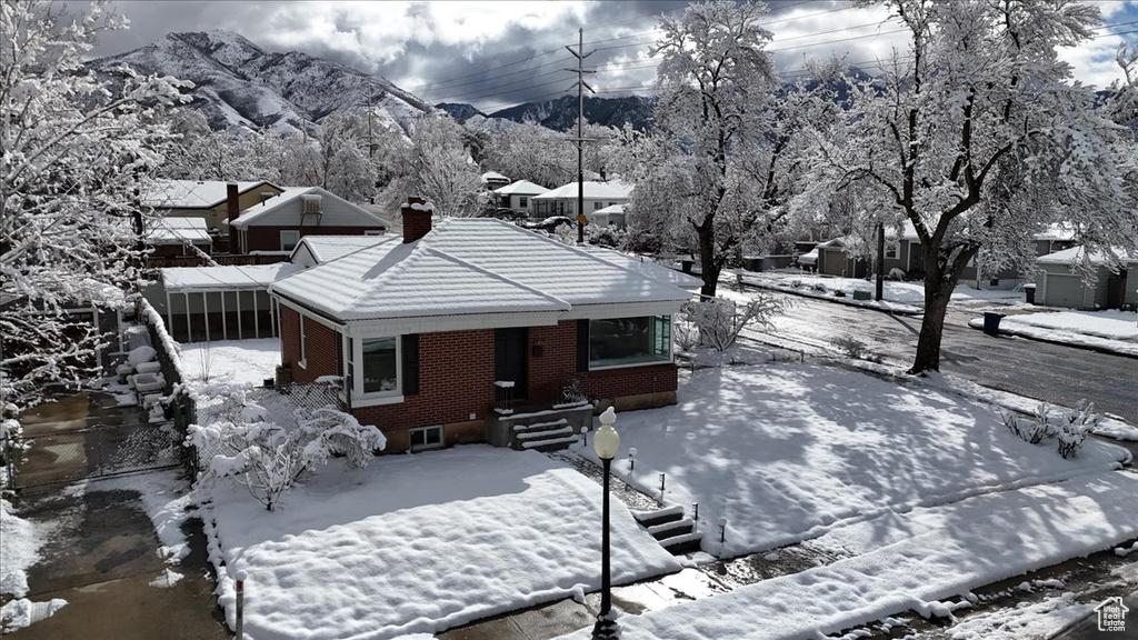 Snow covered back of property with brick siding, a chimney, and a tile roof