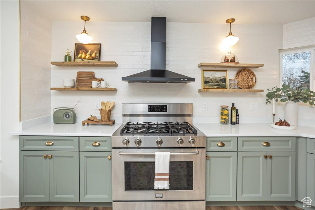 Kitchen with green cabinets, open shelves, wall chimney exhaust hood, and stainless steel gas range