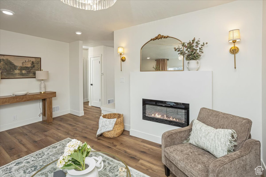 Living room with a glass covered fireplace, recessed lighting, wood finished floors, and baseboards