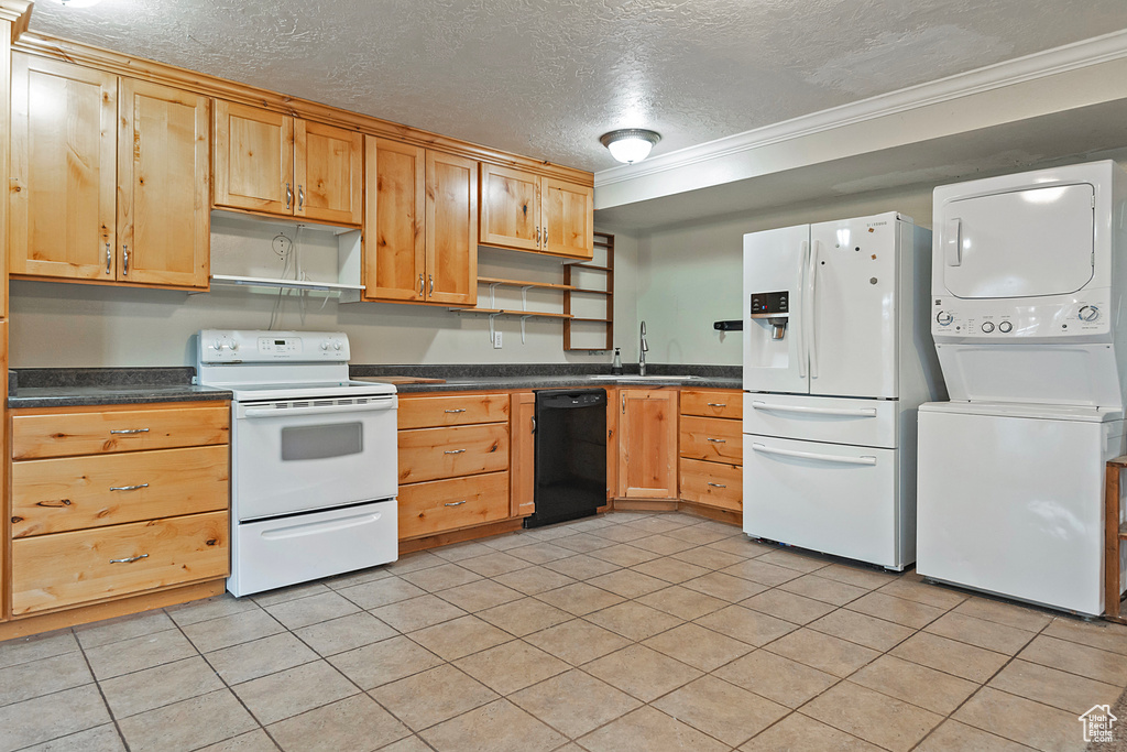 Kitchen with dark countertops, stacked washer / dryer, open shelves, white appliances, and a sink