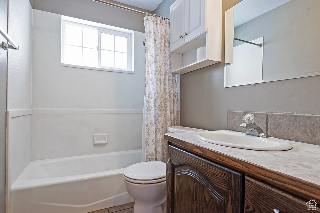 Full bathroom with shower / tub combo with curtain, toilet, and vanity