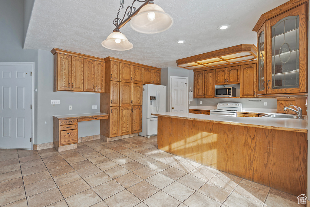 Kitchen with glass insert cabinets, light countertops, brown cabinets, white appliances, and a sink