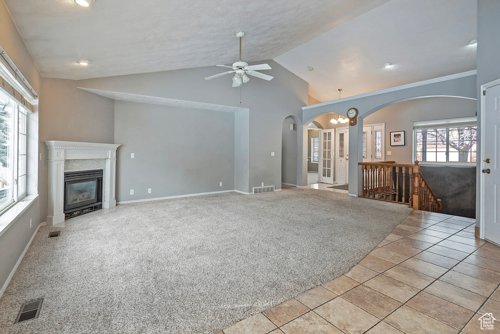 Unfurnished living room featuring a high end fireplace, visible vents, light colored carpet, and lofted ceiling